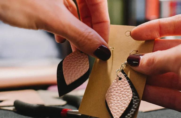 Créatrice présentant une paire de boucles d'oreilles en cuir faites main